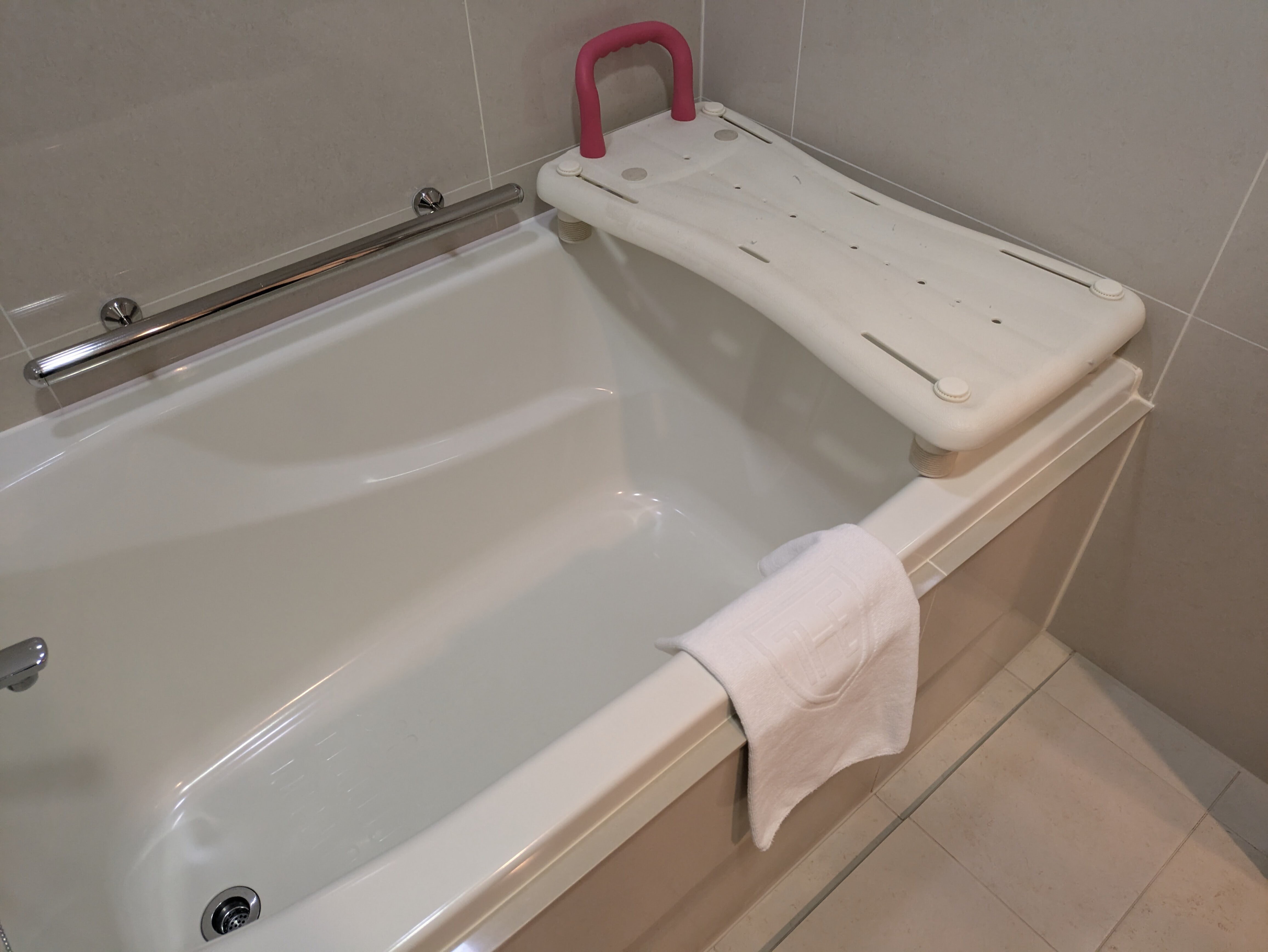Ảnh bồn tắm và bệ đỡ di chuyển trong phòng tắm của phòng hỗ trợ không rào cản